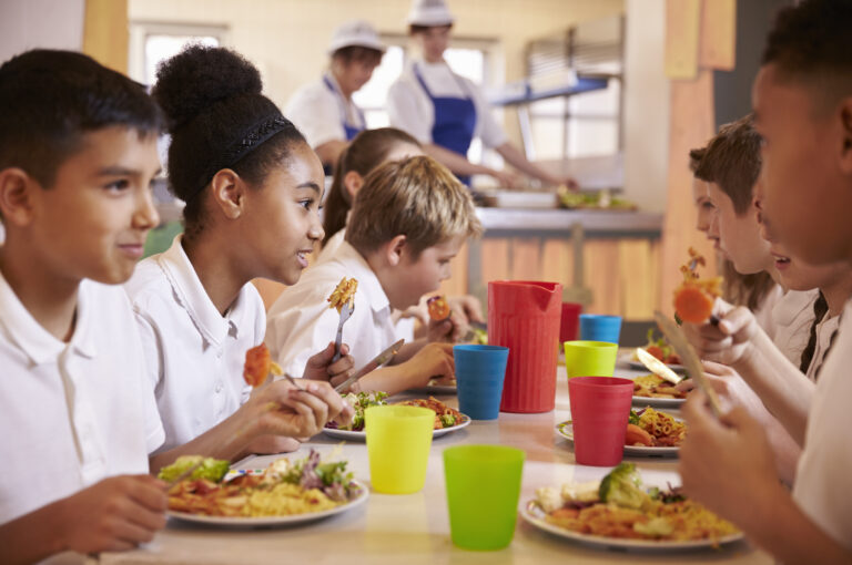 Primary school kids eat lunch in school cafeteria